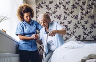 caregiver helping an elderly woman get up