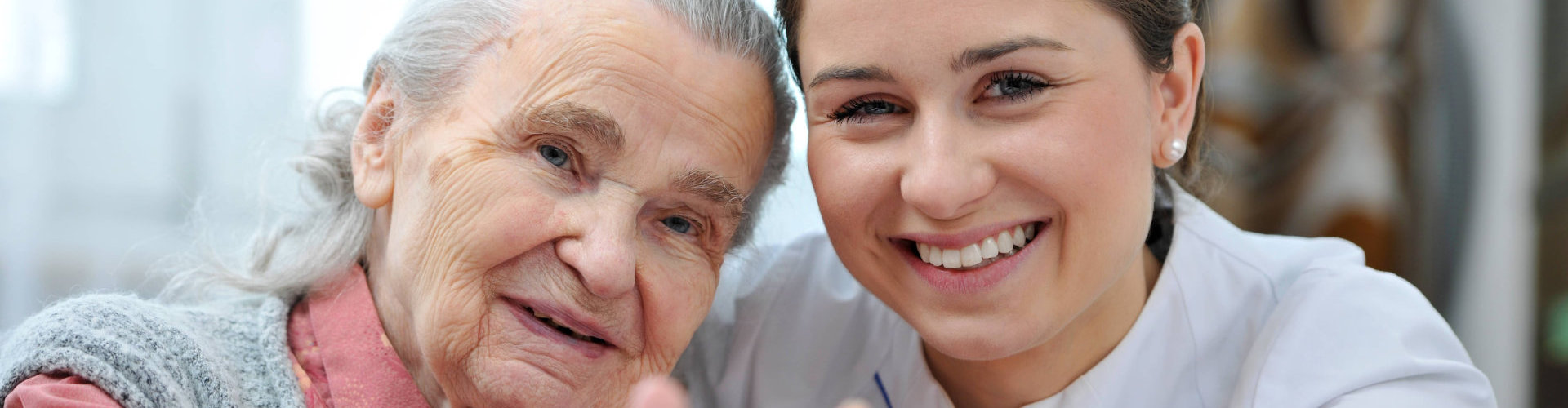 caregiver and an elderly woman smiling at the camera