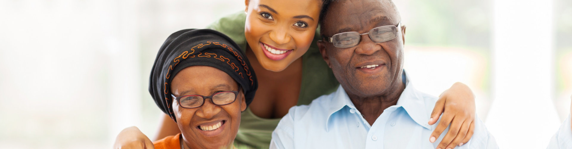 caregiver and an elderly couple smiling at the camera